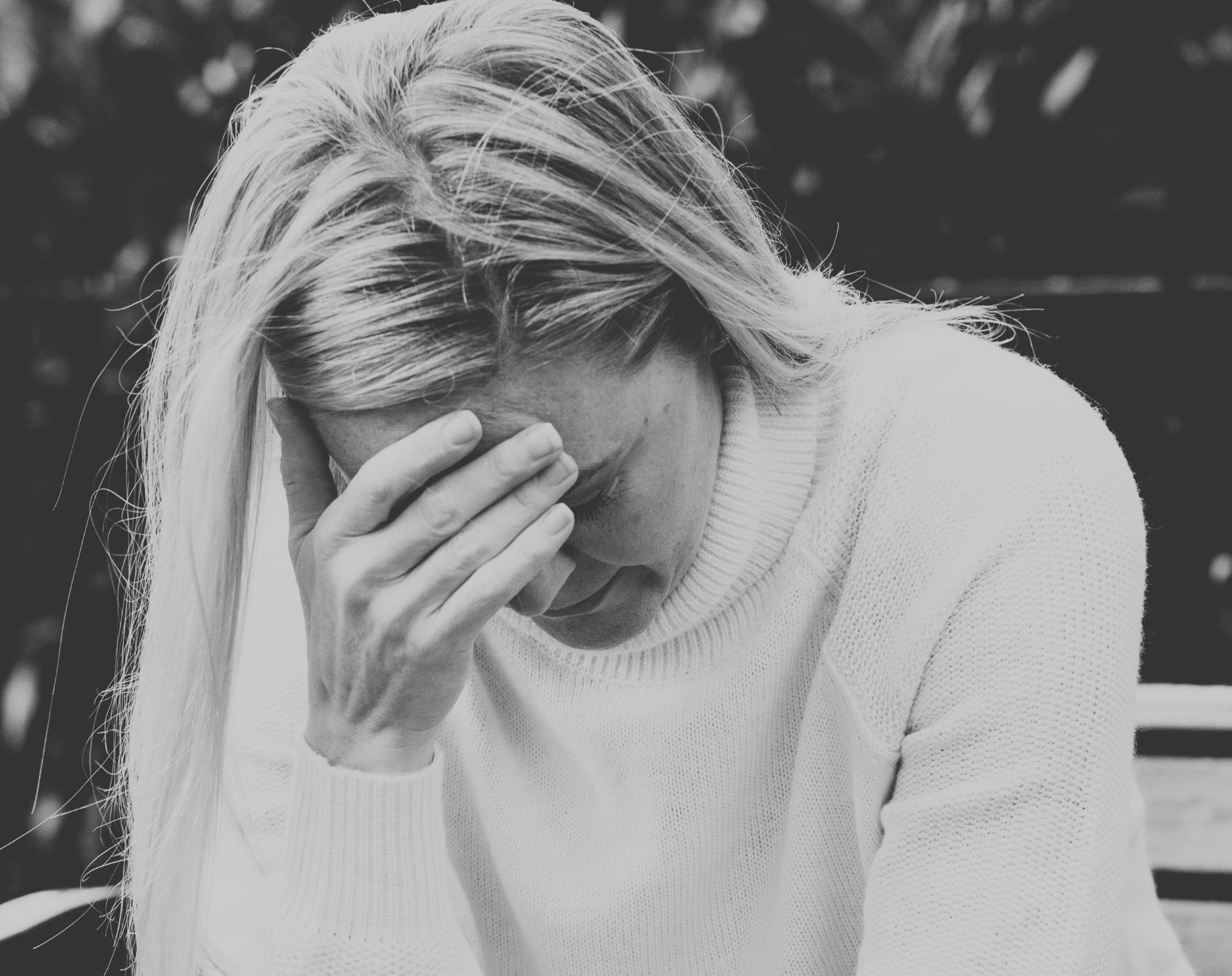 A person holding their head with a migraine, with a subtle MS ribbon, representing the connection and management of migraines with Multiple Sclerosis.