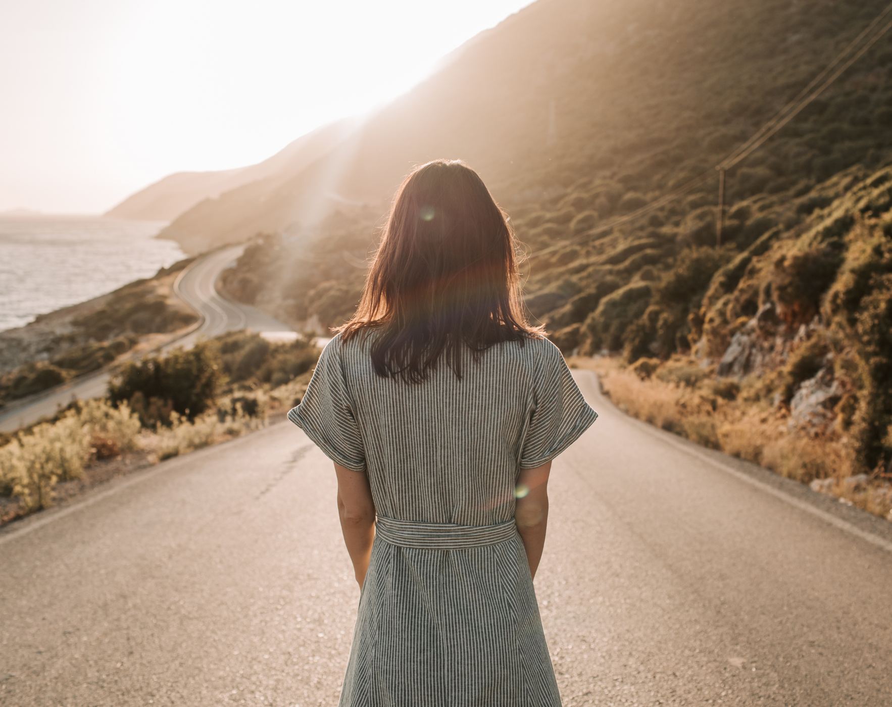 Woman standing at a forked road during sunrise, symbolizing the overwhelm of making health decisions with MS